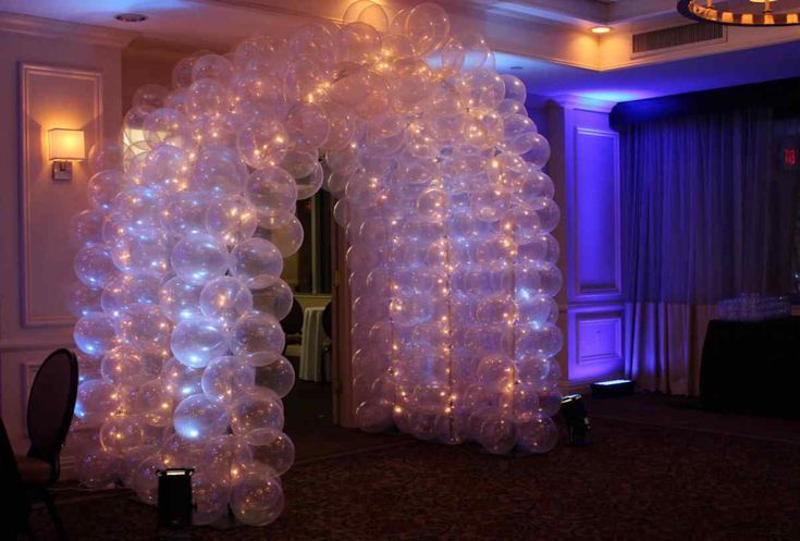 White balloon arch lit with fairy lights in a warmly lit event hall