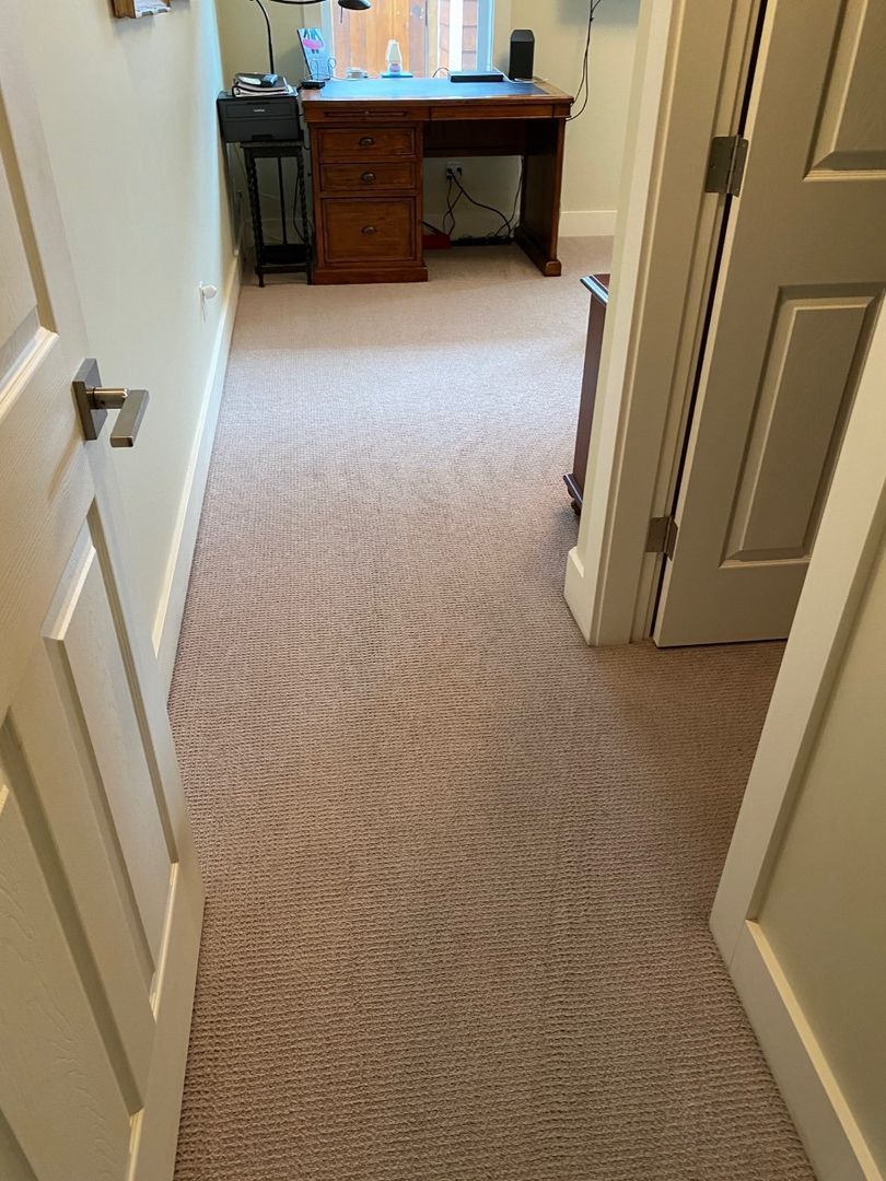 Carpeted hallway leading to a wooden desk at the far end, viewed through an open doorway.