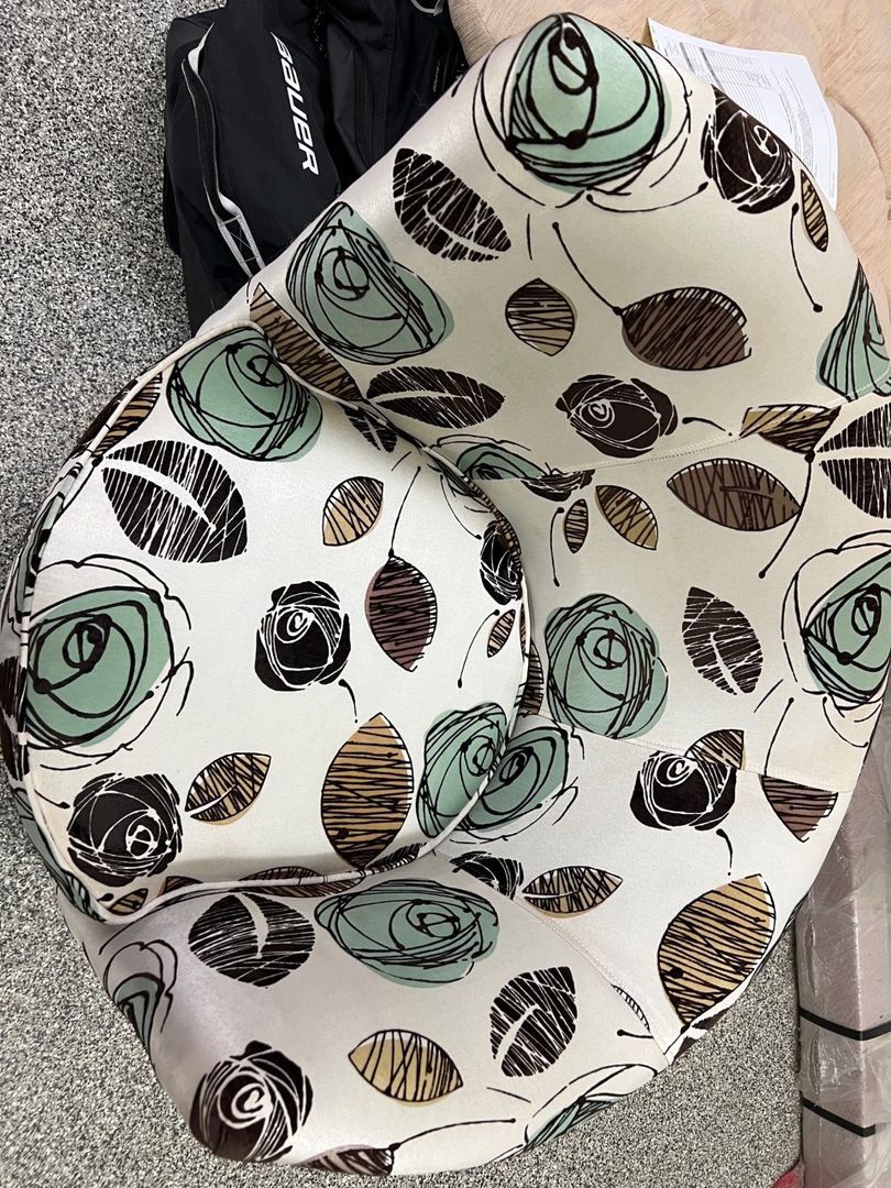 Patterned white scarf with mint green and black circular designs folded on a gray surface