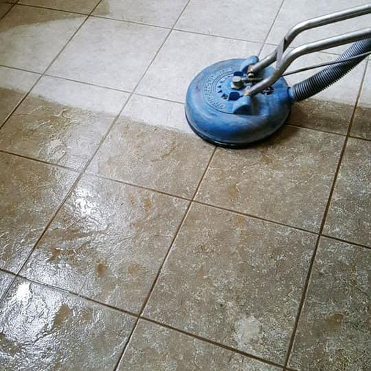 Concrete floor with a window, cleaning equipment, and hoses in a room under construction.