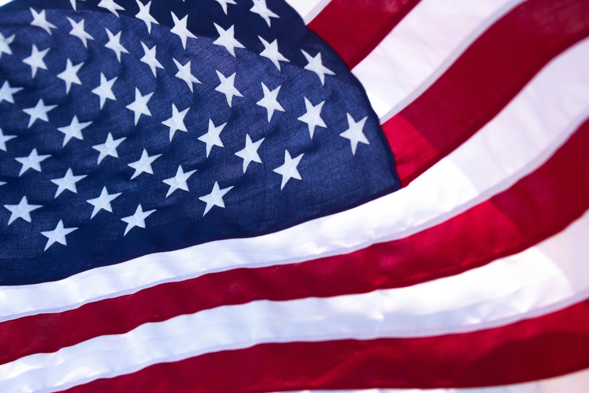 A woman is holding an american flag and a rose at a funeral.