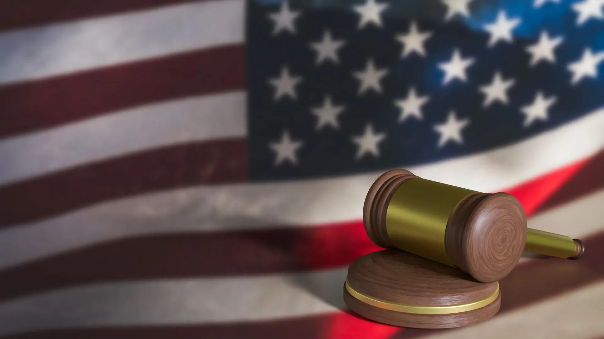Judge’s gavel on a wooden stand before a blurred U.S. flag background