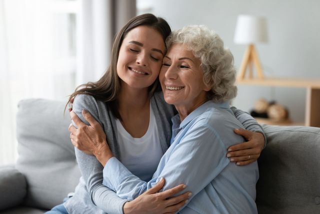 Two people smiling and hugging on a couch in a bright living room