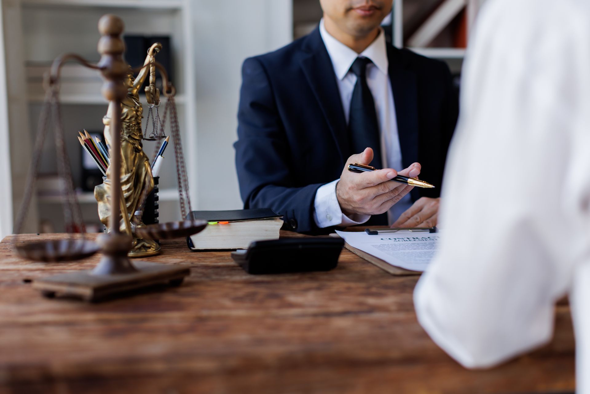 Two lawyers discuss legal matters at a desk with a gavel and scales of justice nearby.