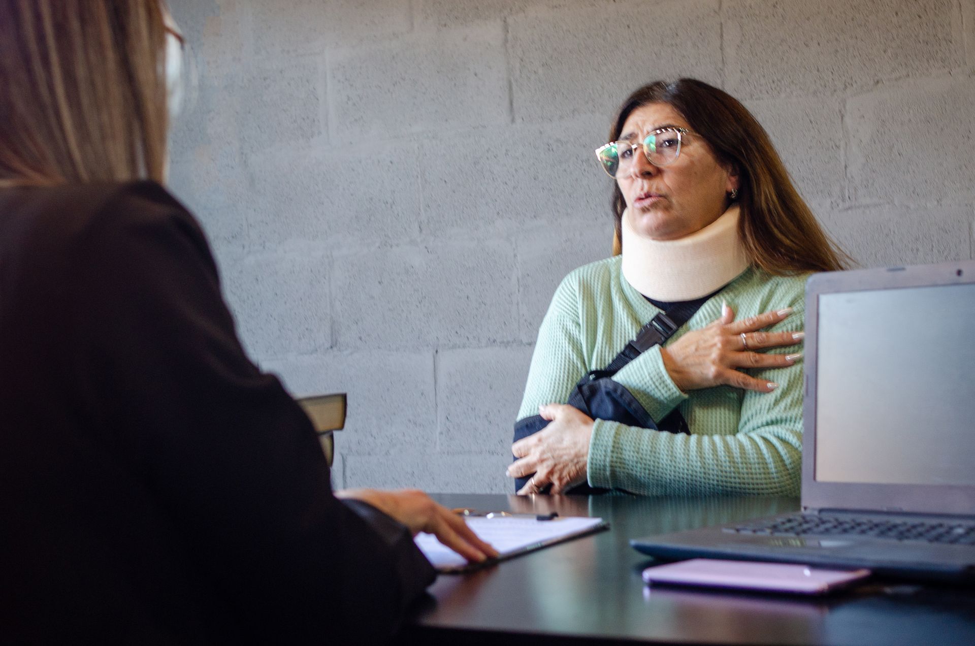 Injured woman in neck brace and arm sling consulting a personal injury attorney.