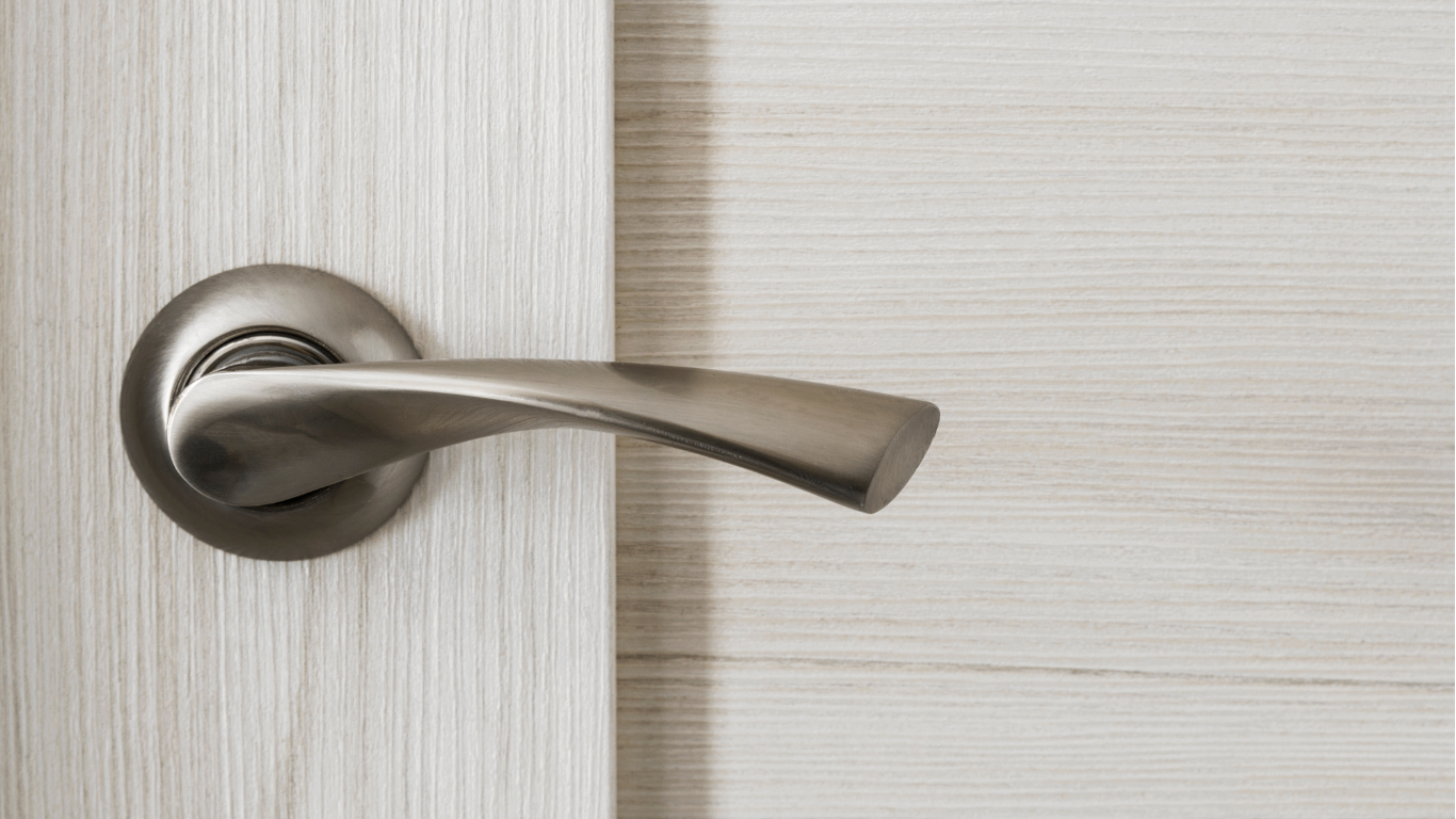 Silver door handle on a white wooden door, close-up shot.