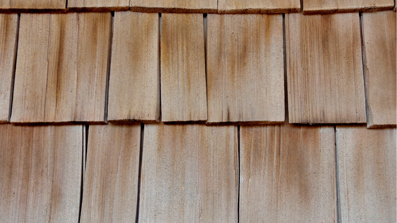 Close-up view of weathered, overlapping cedar wood shingles on a surface.