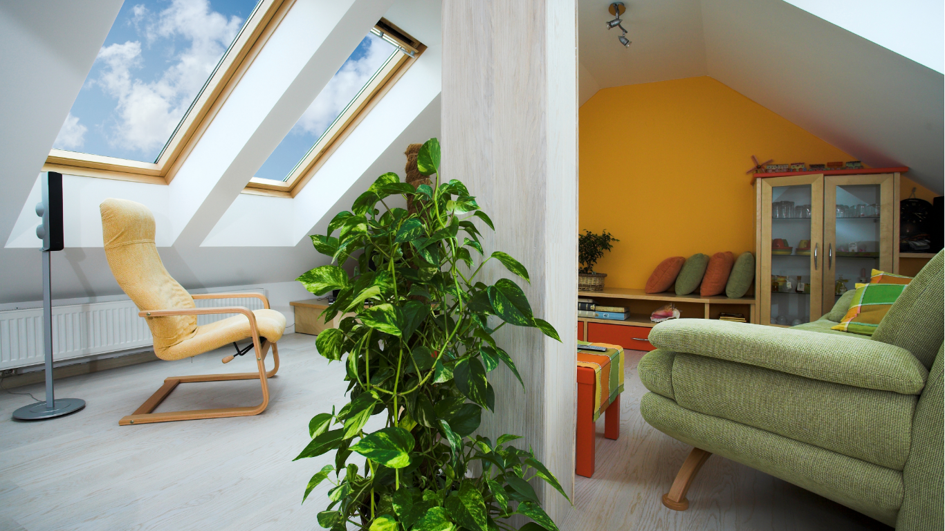 Attic living space with skylights, armchair, and indoor plant. Adjacent living area with yellow wall and green sofa.