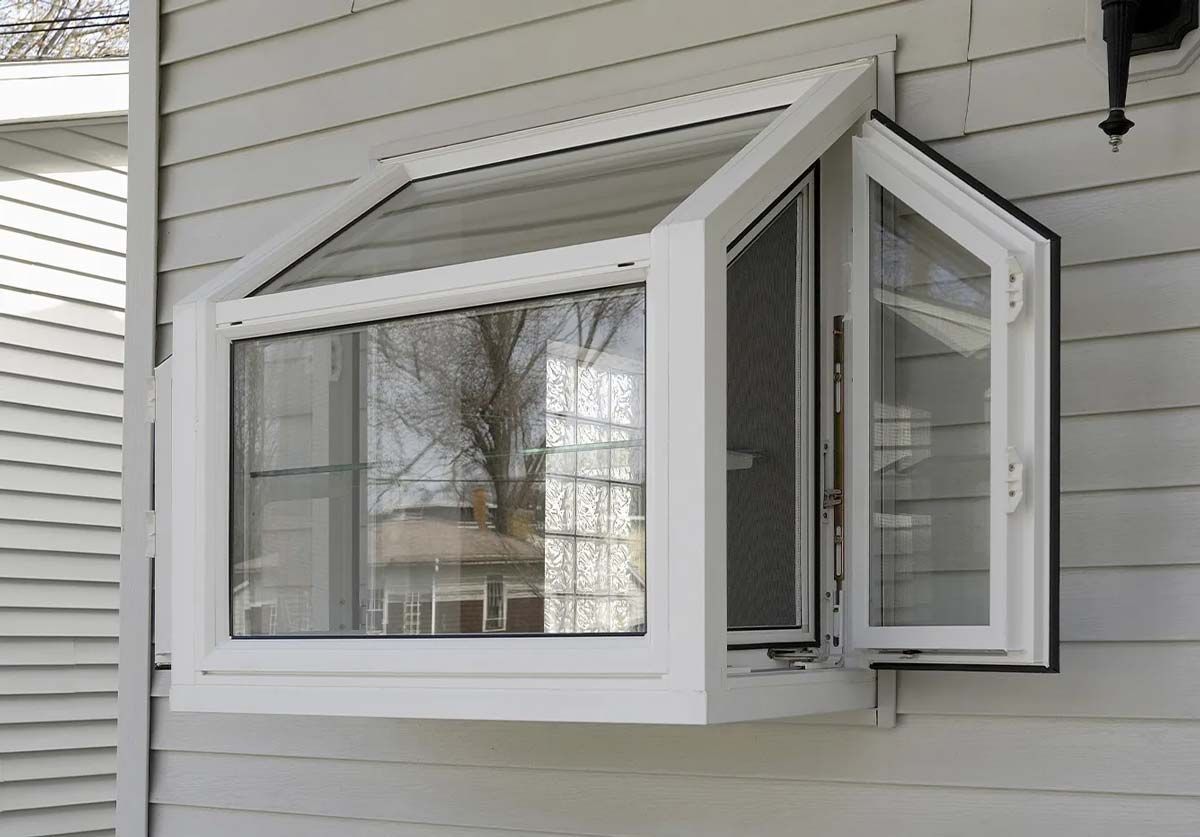 White bay window on a light-colored house; two side panels open outward, center panel closed.
