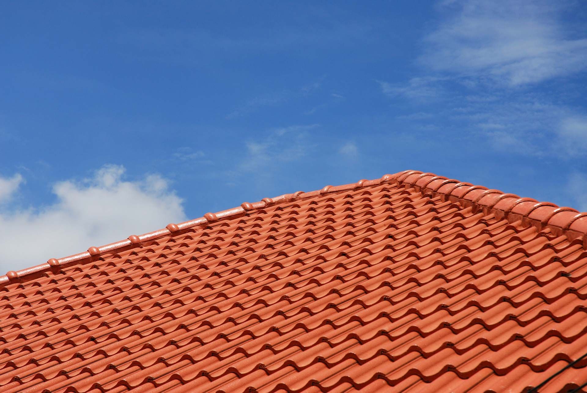 Orange tile roof against a blue sky with some white clouds.