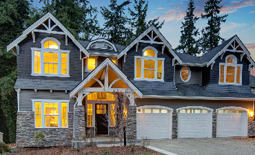Two-story gray house with stone accents, multiple gables, arched windows, and three garage doors.
