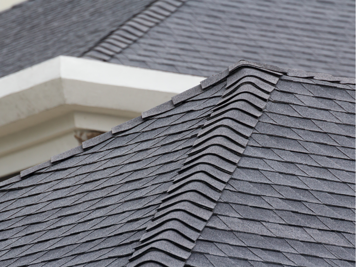 Roof partially replaced on a building, with exposed wood and black tiles. A crane assists with the work.