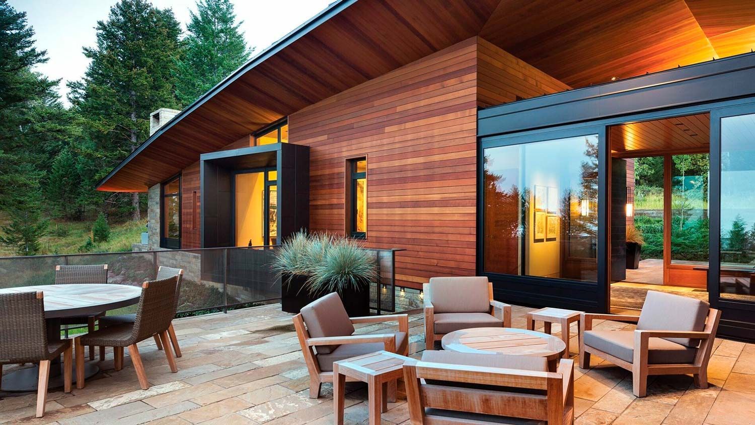 Modern home with wood siding and a patio with seating.