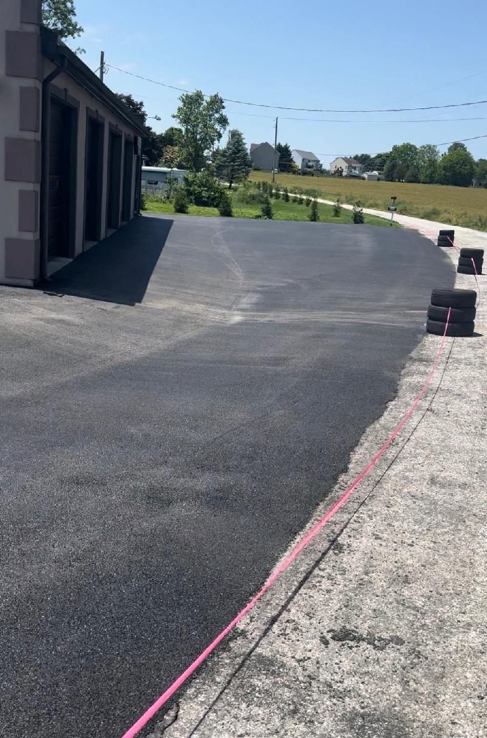A black asphalt driveway is being built in front of a house.