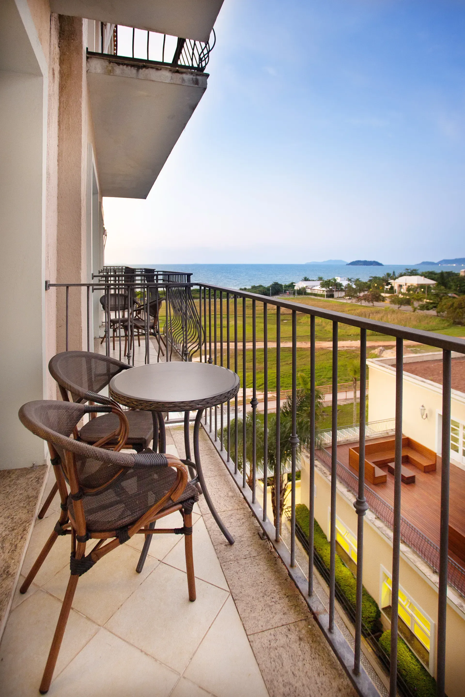 Terraço no quintal com duas banheiras de hidromassagem octogonais e um guarda-corpo de vidro com vista para as árvores e a água.