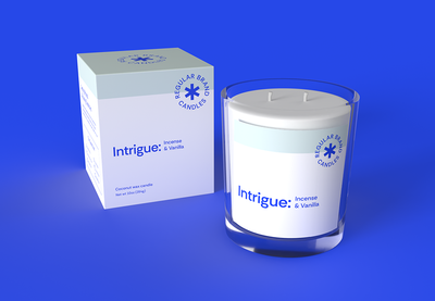Blue product box and candle labeled “Intrigue” on a blue background