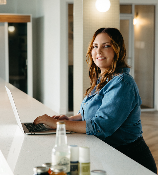 Woman using a laptop at a bright counter in a modern kitchen