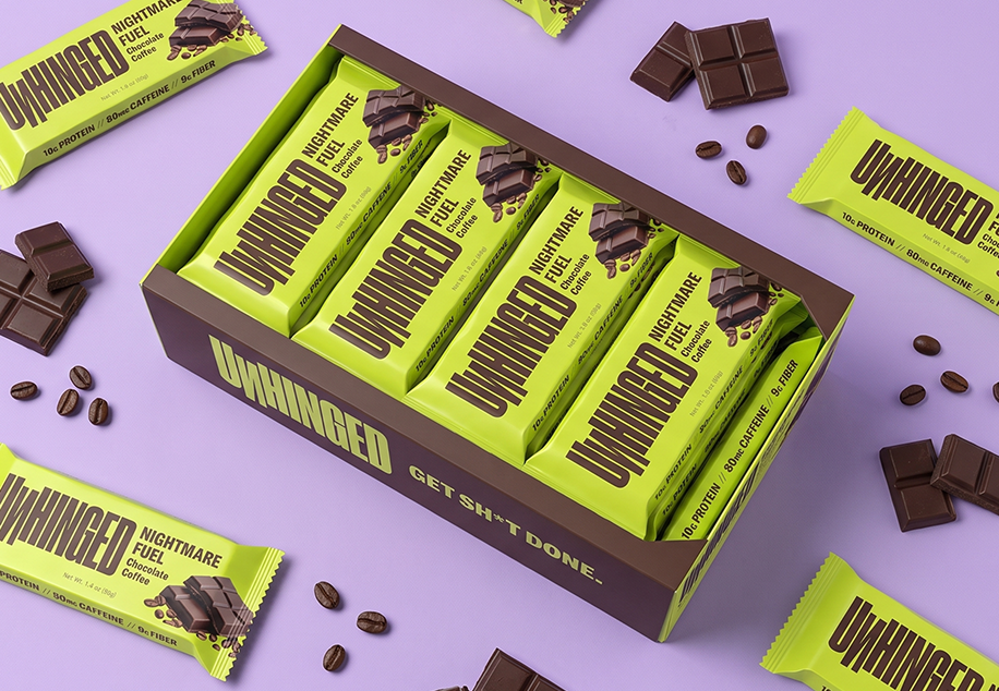 Open chocolate box with bright green bars and scattered pieces on a purple background
