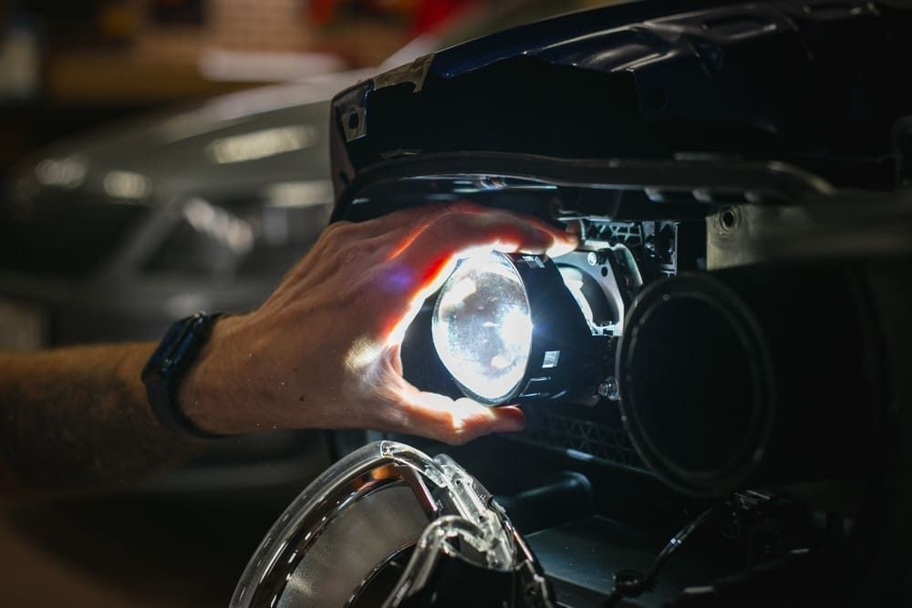 A Person Is Fixing A Car Headlight In A Garage — 4off Automotive & Electrical In Bowral, NSW