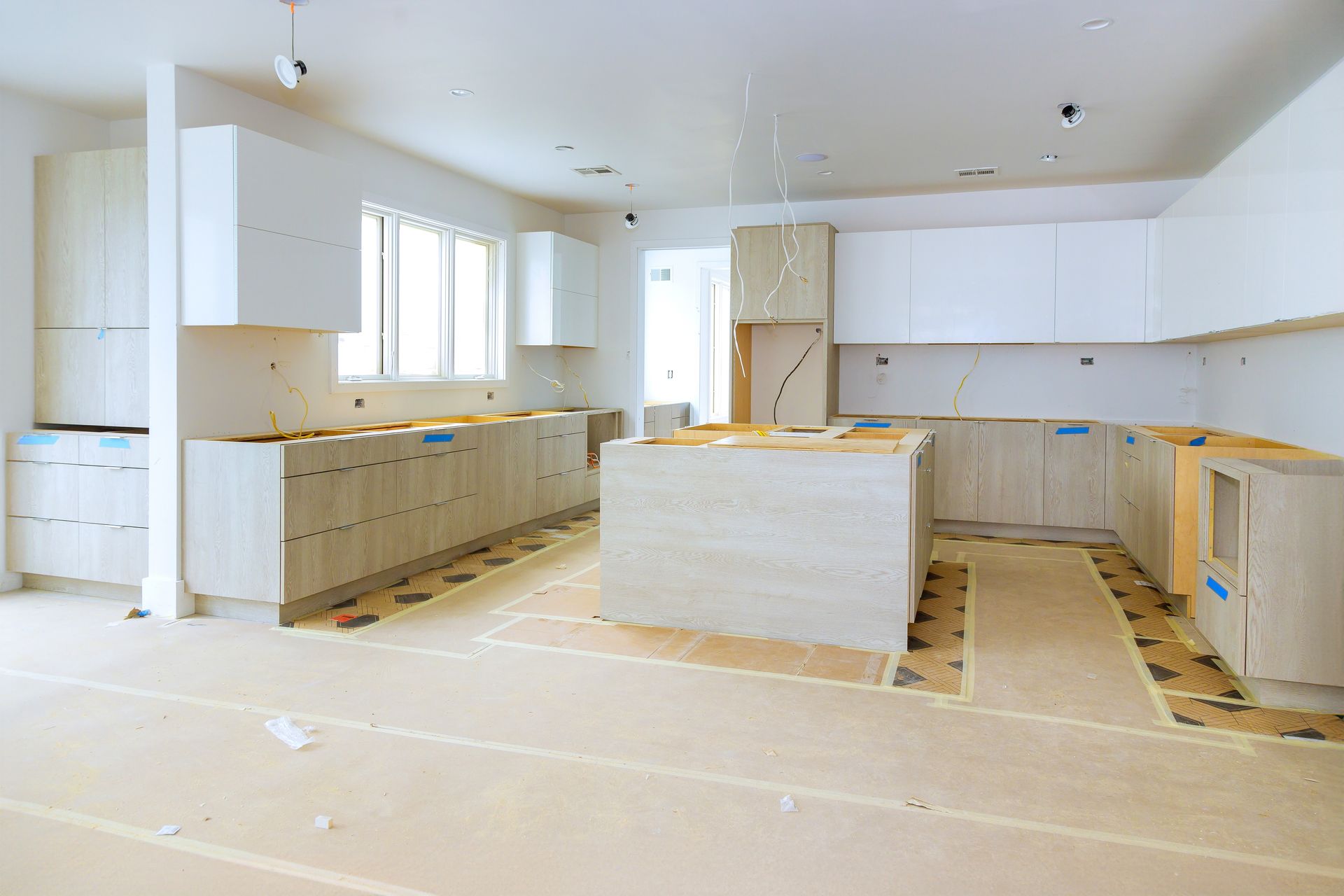 Unfinished modern kitchen with white cabinets, island, and protective floor covering