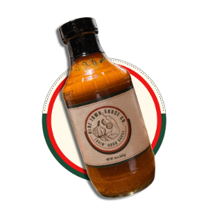 Amber bottle with a black cap and circular label, tilted over a red and green ring on a white background