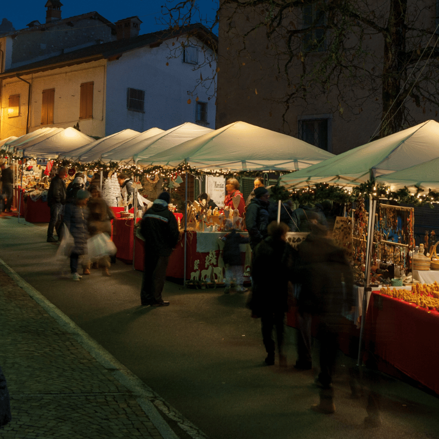 Night market stalls under white tents on a dimly lit street, with people browsing goods.