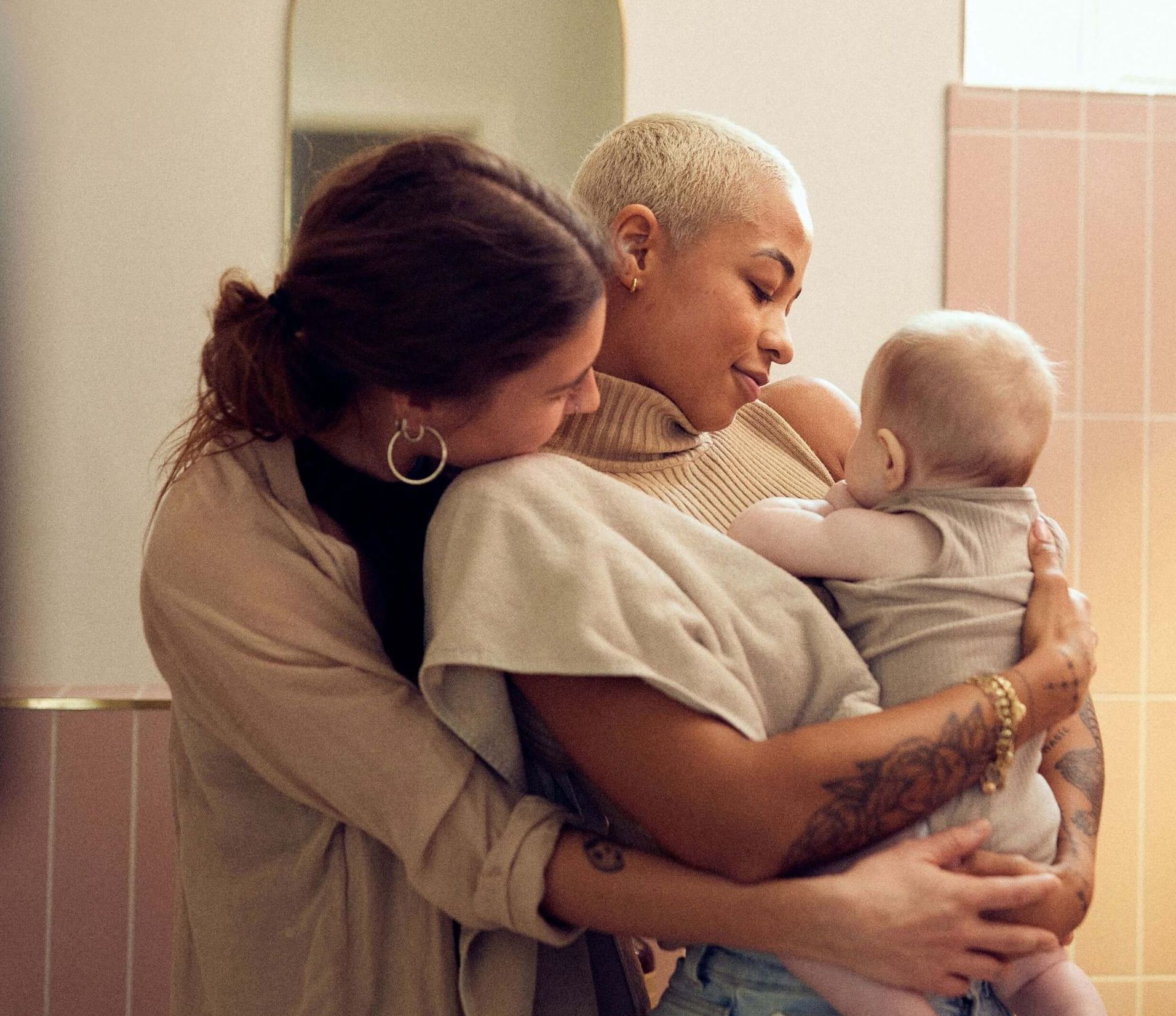 Deux femmes tiennent un bébé dans une salle de bain.