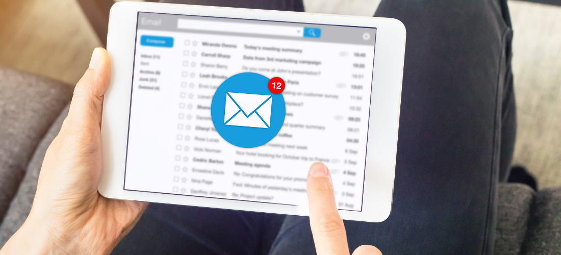 A person is holding a tablet with an envelope on the screen.