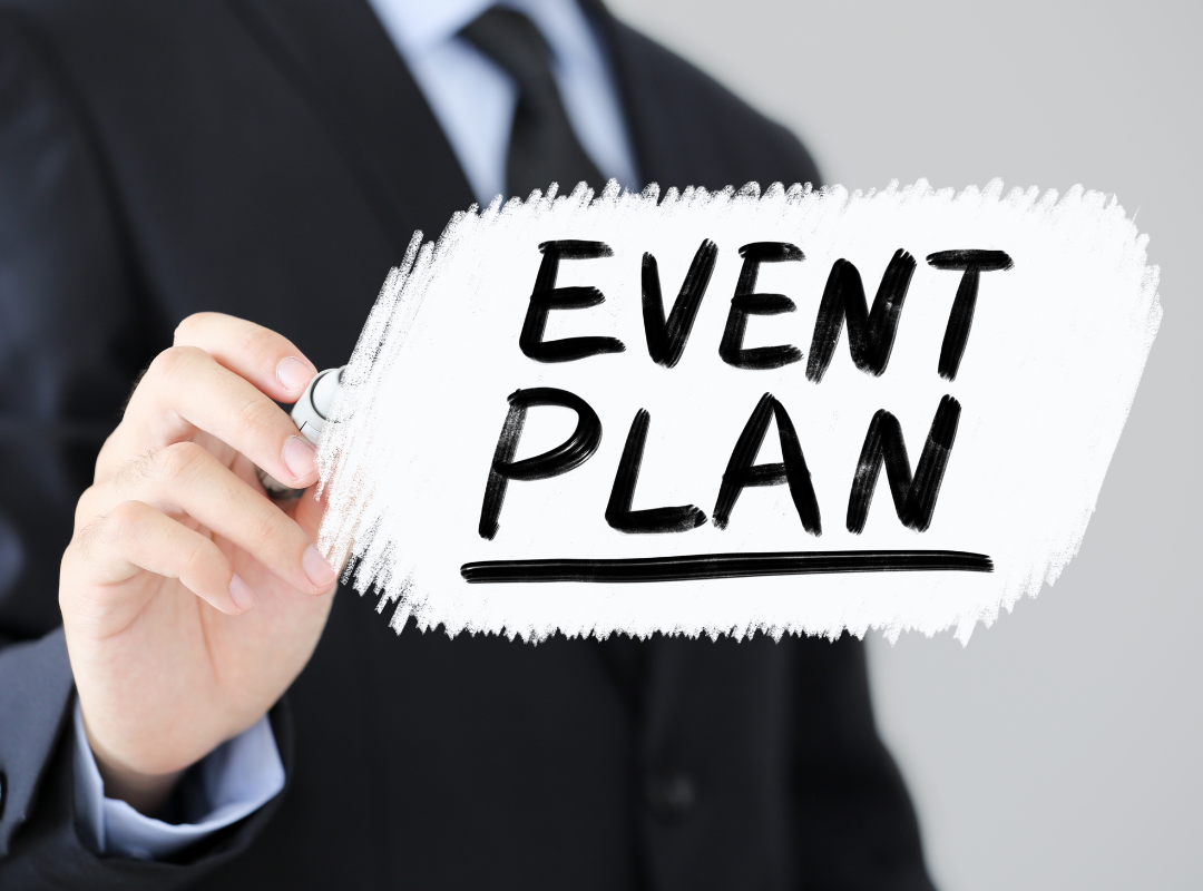 A man is writing the word event plan on a white board