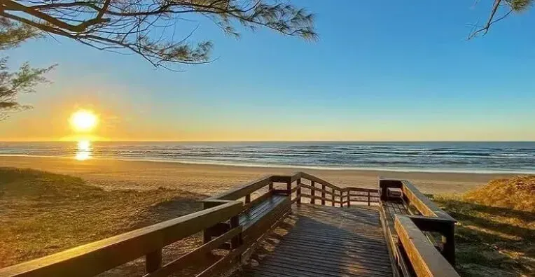 Uma passarela de madeira que leva à praia ao pôr do sol em Capão da Canoa