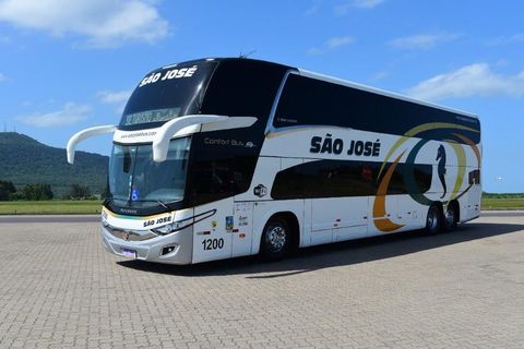 Um ônibus da Expresso São José de dois andares está estacionado em uma estrada de paralelepípedos.