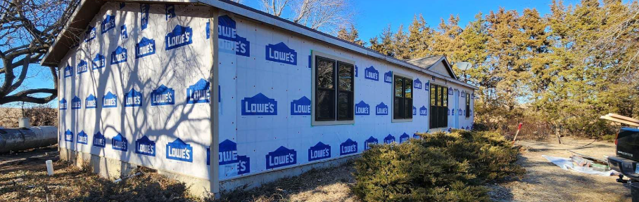 A large white house is being built in the middle of a forest.
