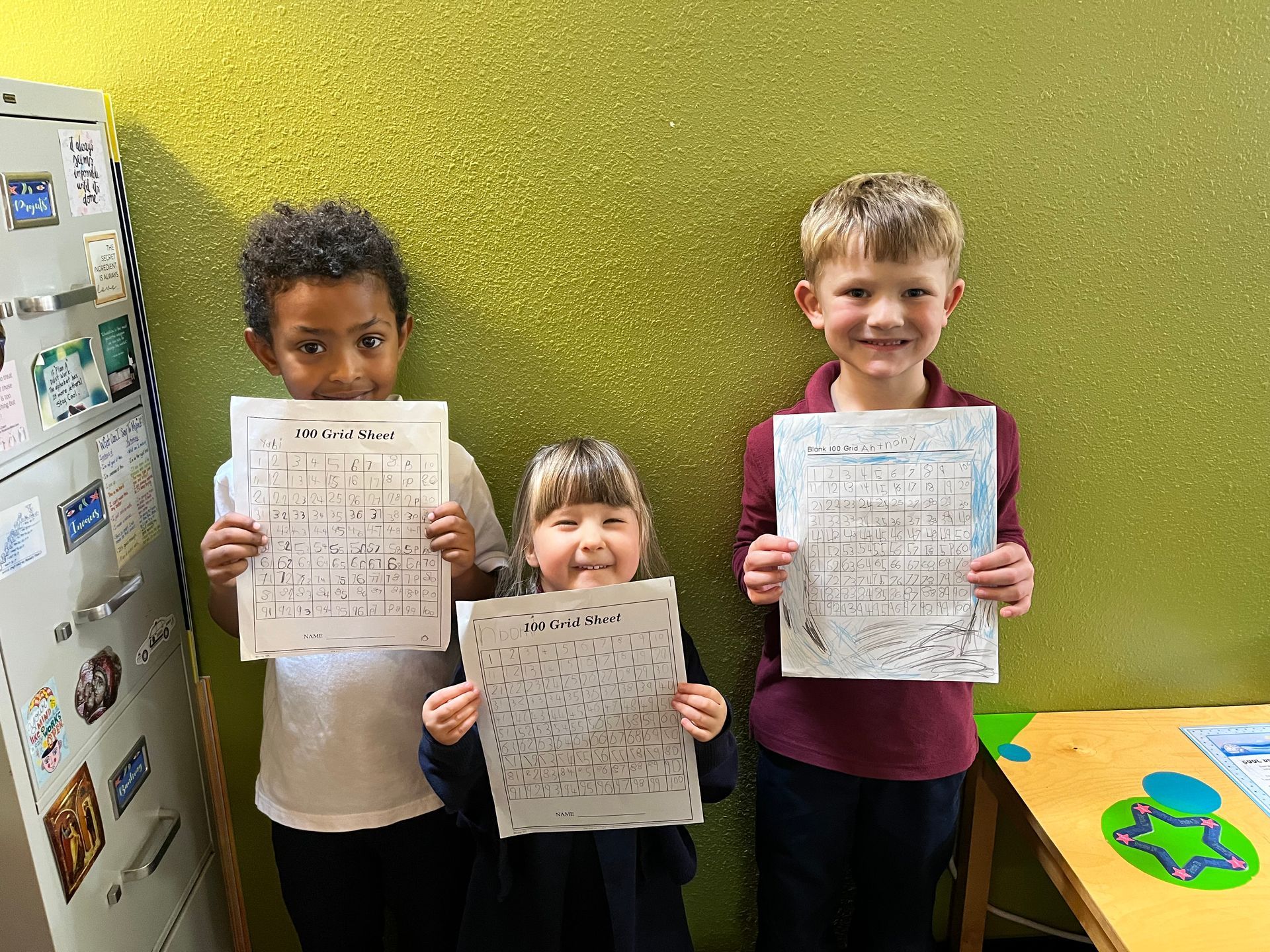 Three kids showing their activity sheets.