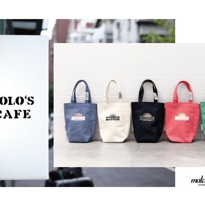 Four bags are lined up in front of a white wall.