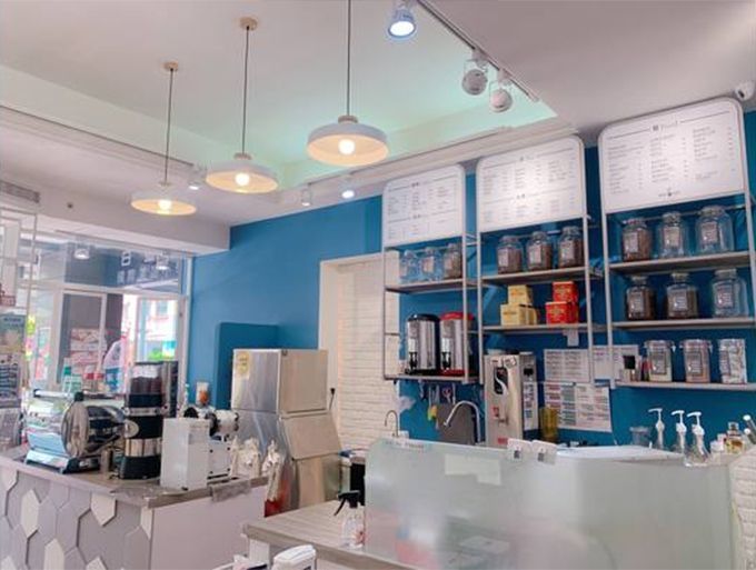 The inside of a coffee shop with blue walls and shelves.