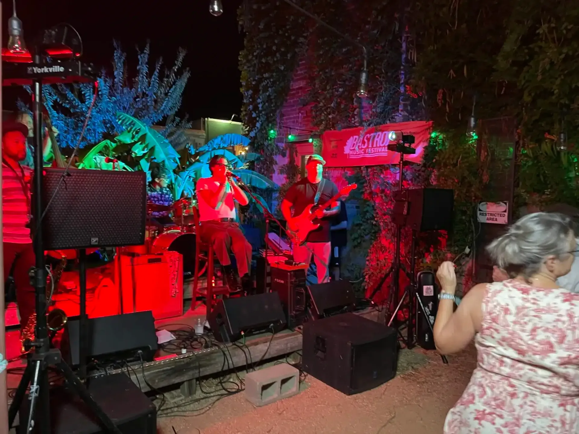 Live band performing on a colorful outdoor stage, with a woman dancing in the foreground.