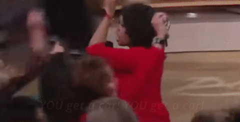 a woman in a red shirt is standing in front of a crowd of people .