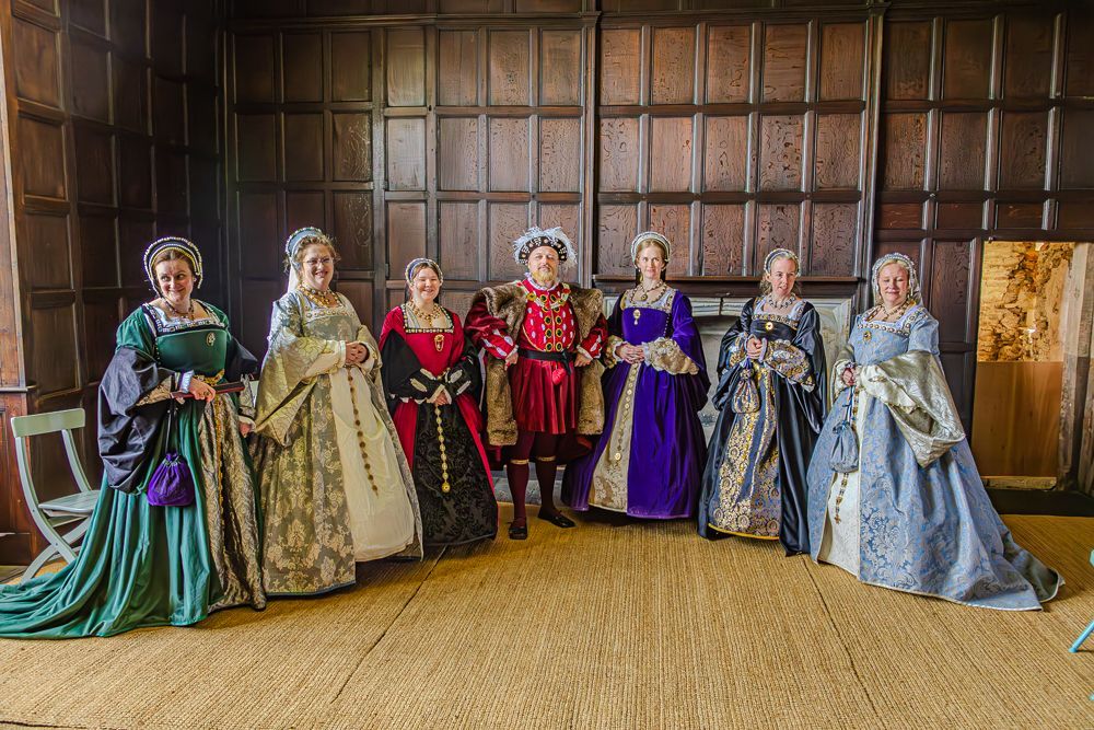 A group of people dressed in Tudorcostumes are standing next to each other in a room.