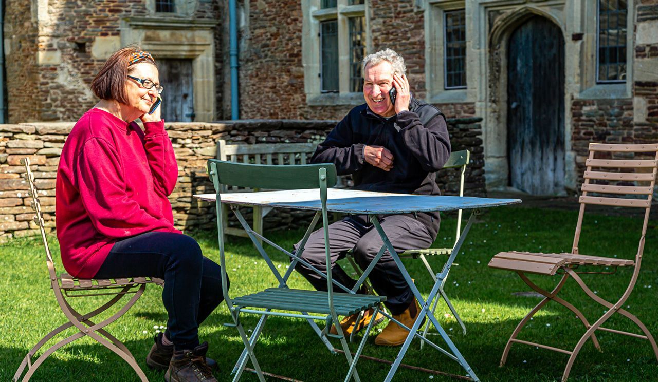 A man and a woman are sitting at a table listening to audio tours