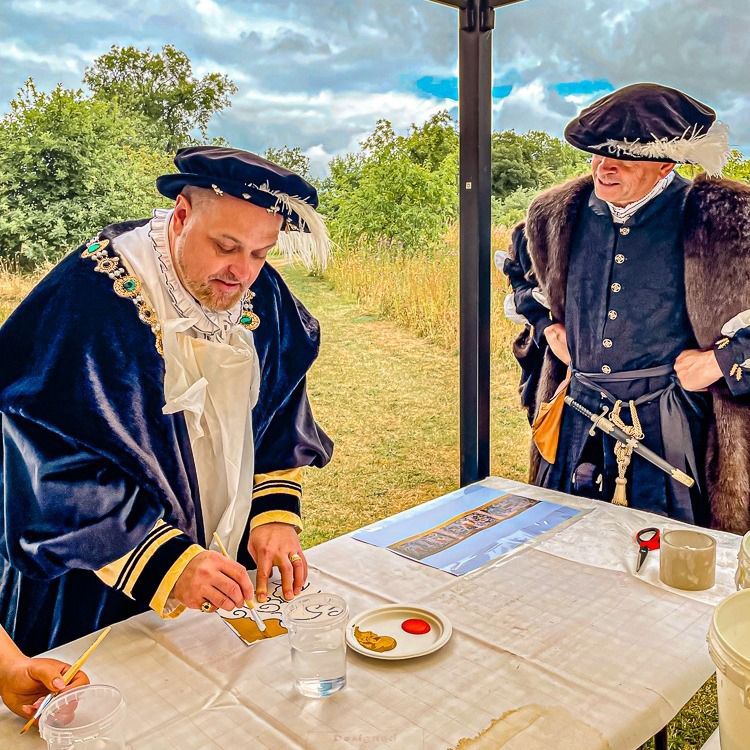 Two men in medieval costumes are sitting at a table.
