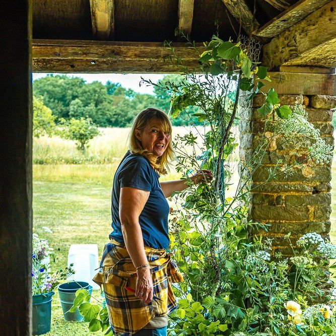 A woman is standing in a doorway looking out at a field.