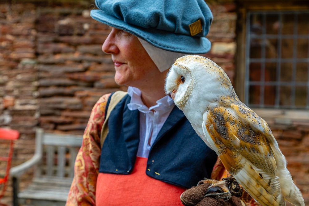 A woman is holding an owl on her shoulder.