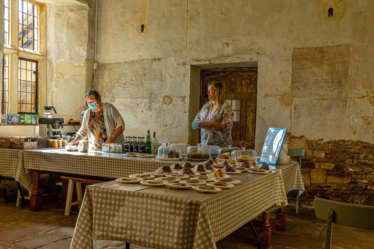 Two women are standing behind a table with plates of food on it.