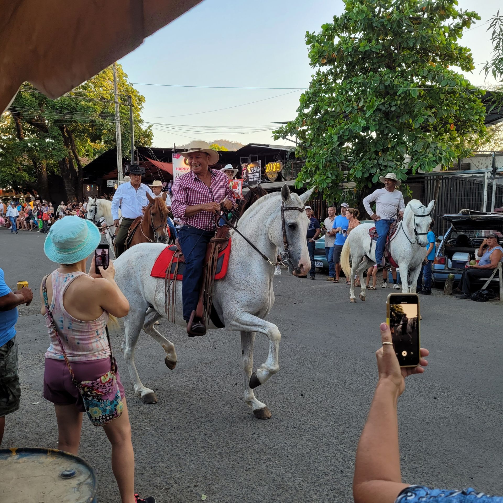 People on horseback in a street parade; spectators taking photos.