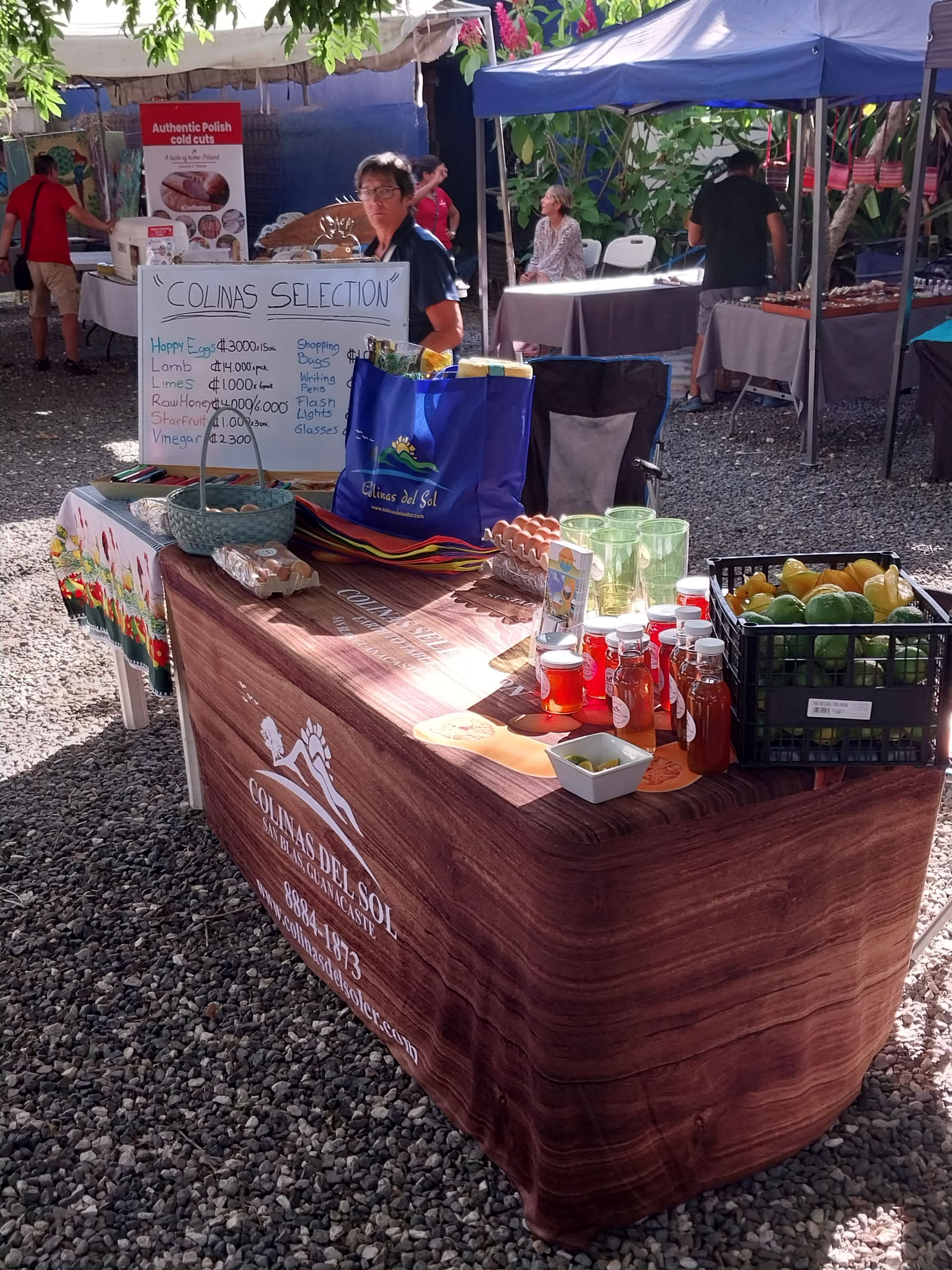 Market stall with vendor, products on display, including jars, lemons, limes.