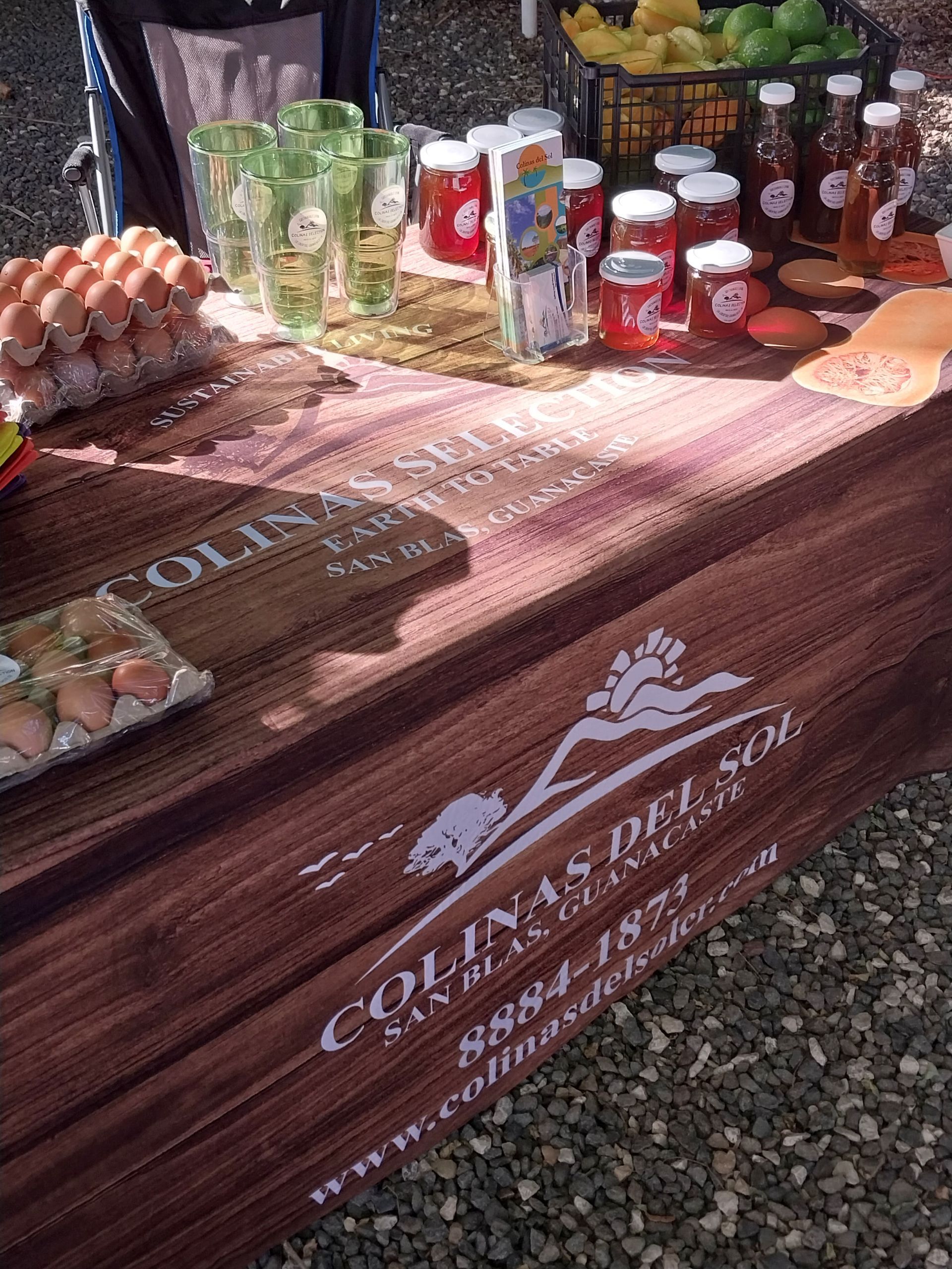 Market table with eggs, jars of jam, drinks, and a sign for