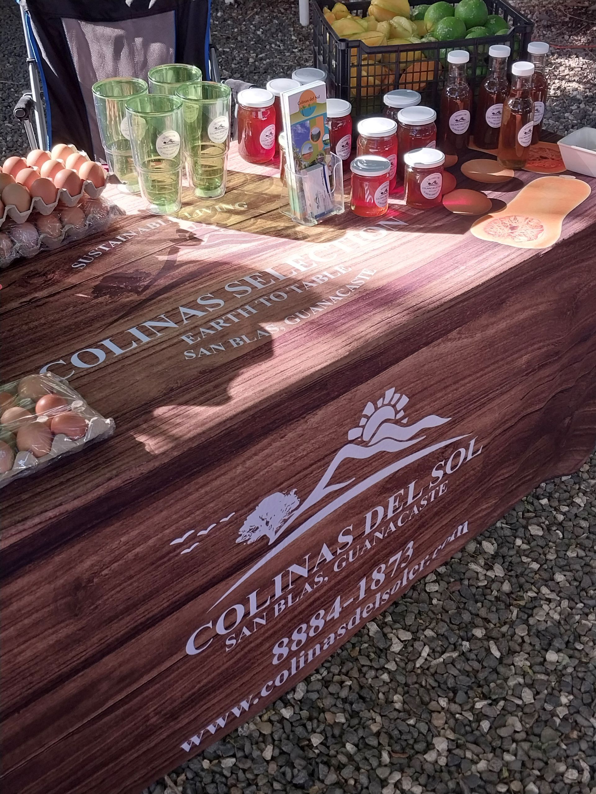Farm stand display: eggs, jams, and drinks on a wooden table with the