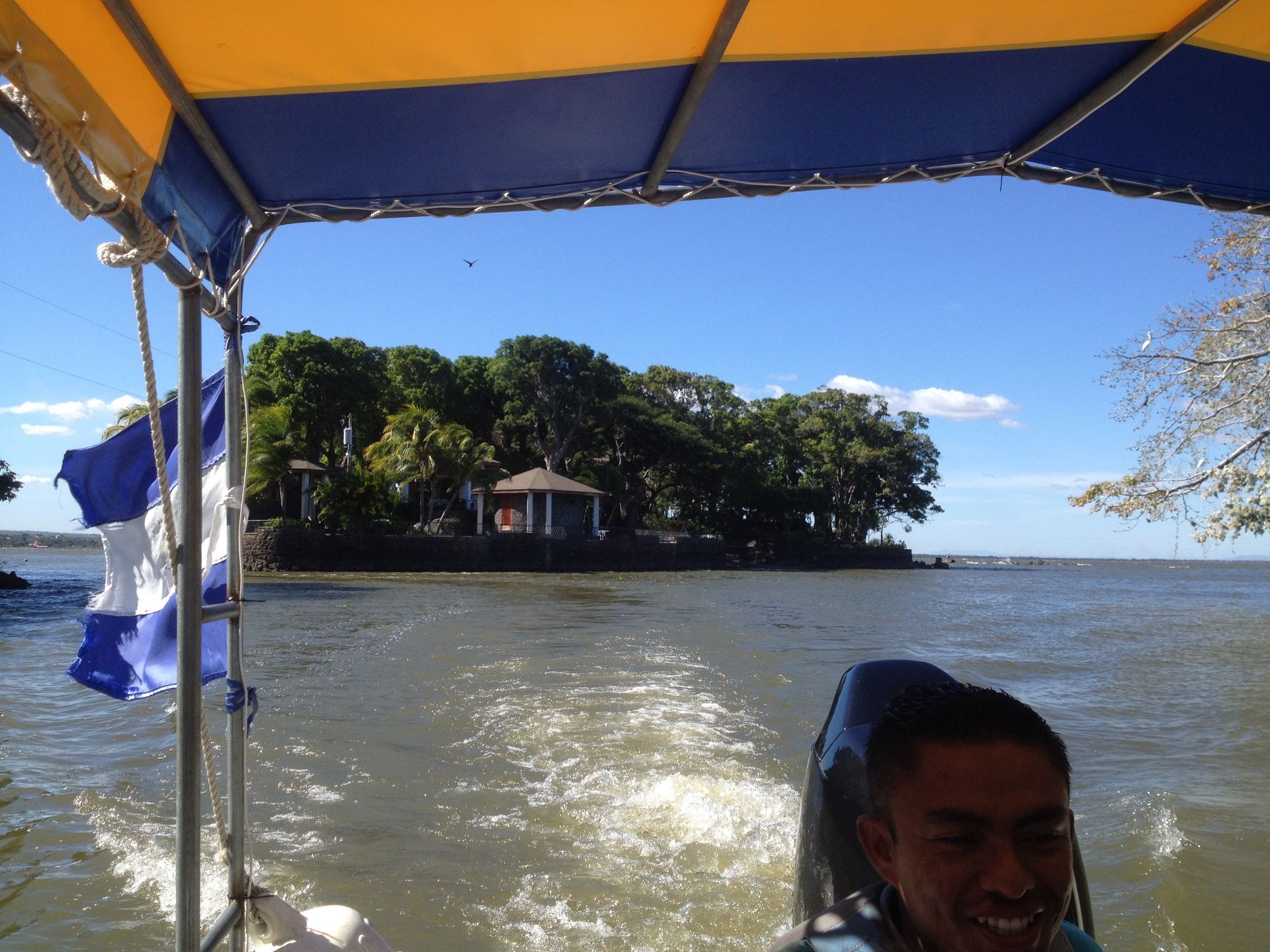 Boat ride on a lake with small island in view; blue sky, sunny day.
