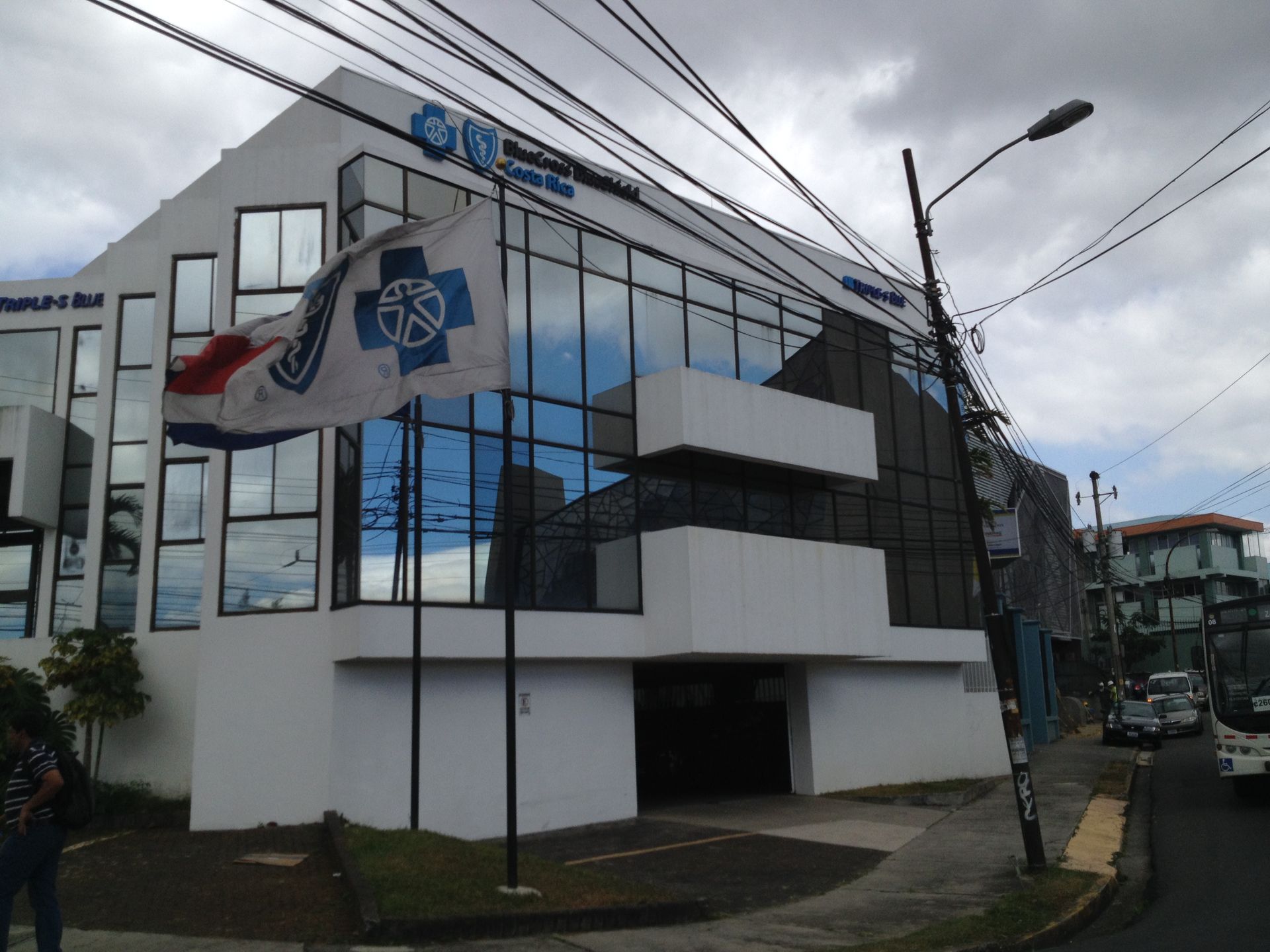 Hospital building with flag, blue and white facade. Cloudy sky, street view.