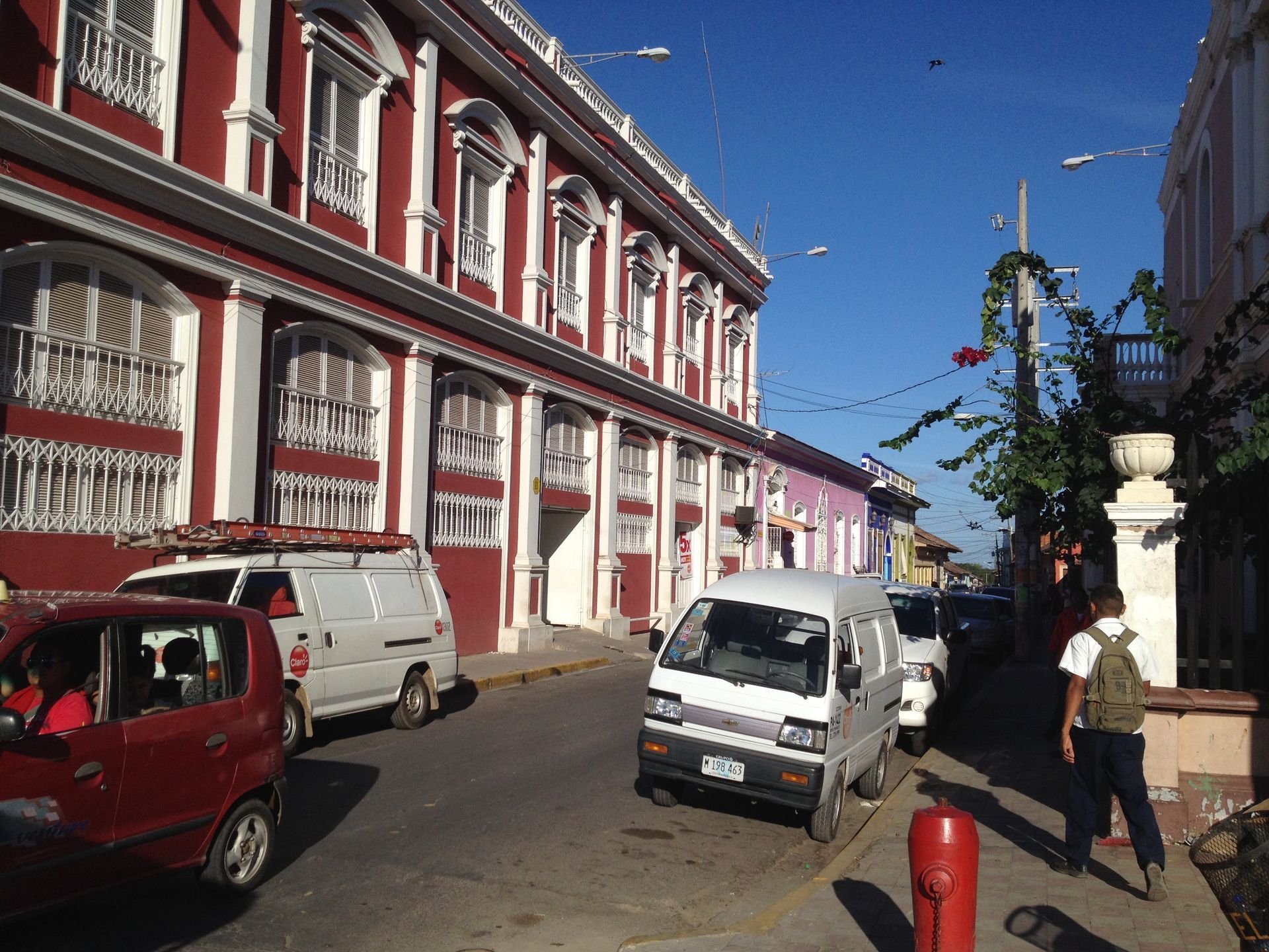 Street scene with colorful buildings, cars, and a person walking.